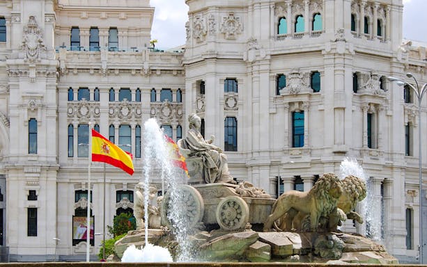 Cibeles Fountain with Spanish flags in front of Palacio de Cibeles, Madrid, Spain.