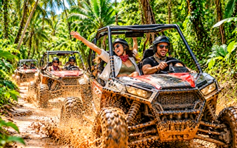 Tourists driving buggies through a muddy jungle trail in Punta Cana.