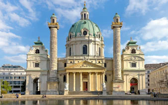 Karlskirche in Vienna with its iconic dome and columns, viewed from the front.
