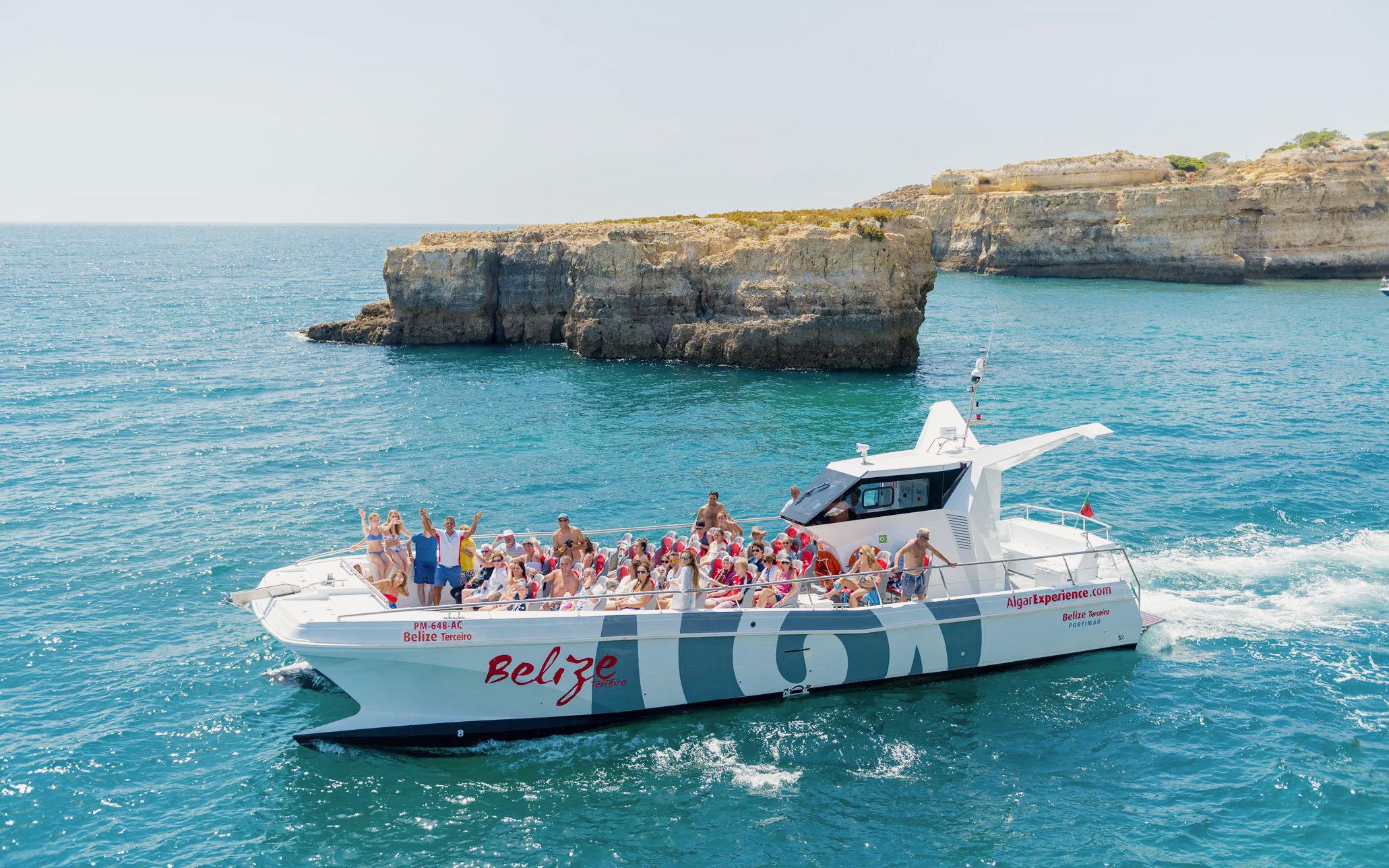 Tourists on a catamaran near Benagil caves during a dolphin tour in Algarve, Portugal.