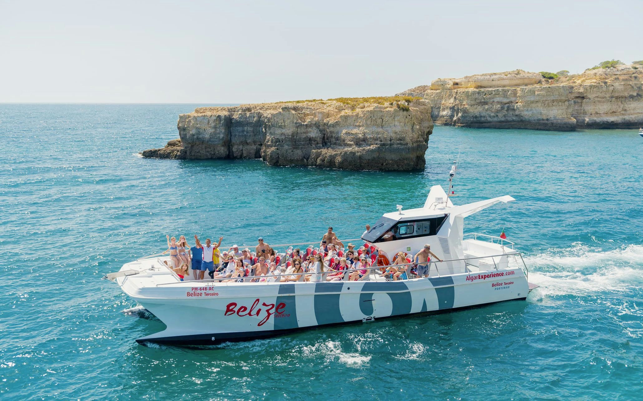 Tourists on a catamaran near Benagil caves during a dolphin tour in Algarve, Portugal.