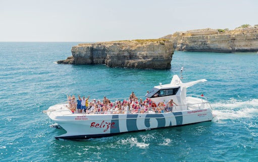 Tourists on a catamaran near Benagil caves during a dolphin tour in Algarve, Portugal.