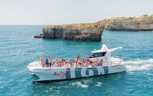Tourists on a catamaran near Benagil caves during a dolphin tour in Algarve, Portugal.