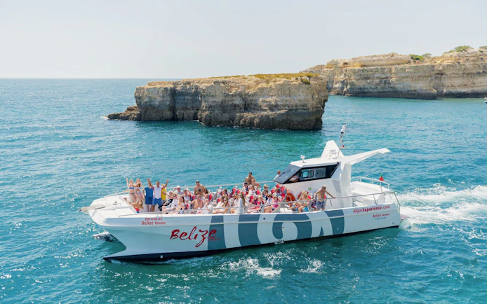 Tourists on a catamaran near Benagil caves during a dolphin tour in Algarve, Portugal.