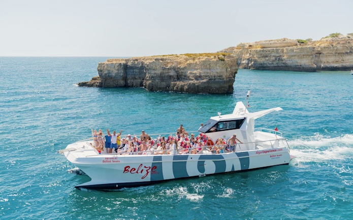 Tourists on a catamaran near Benagil caves during a dolphin tour in Algarve, Portugal.