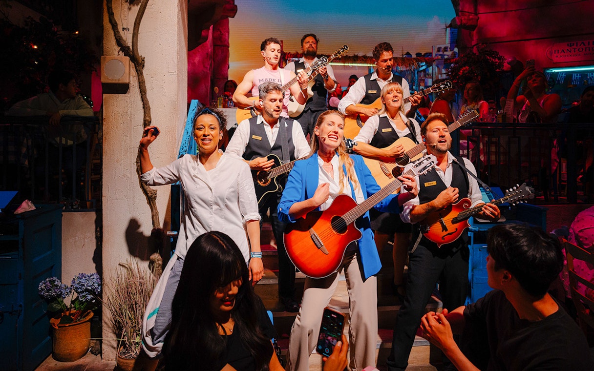 Performers playing guitars and singing at Mamma Mia! The Party event.