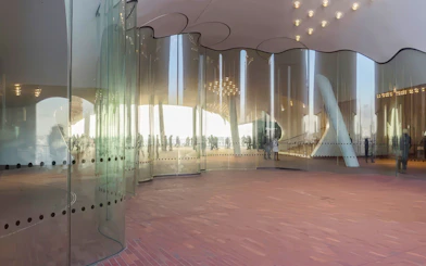 Curved glass walls at Elbphilharmonie Plaza, Hamburg, reflecting visitors and cityscape.