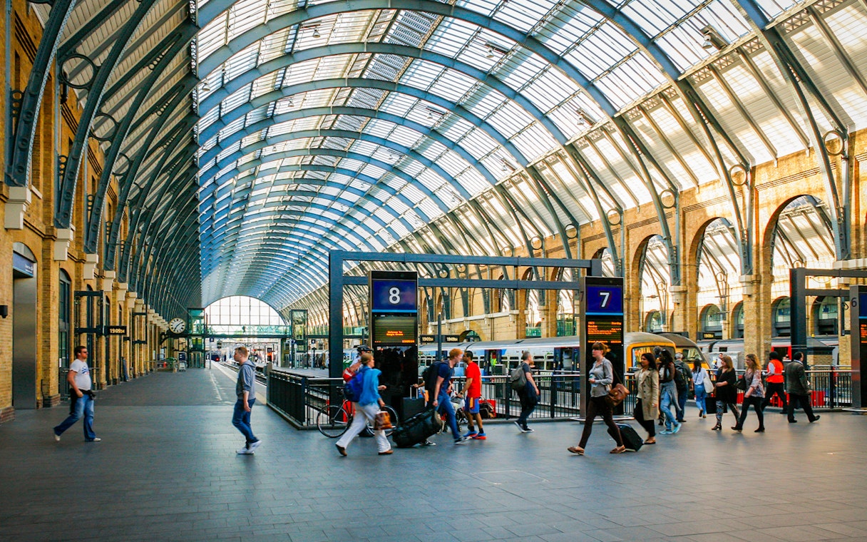 Kings Cross Station interior with travelers and trains, London.