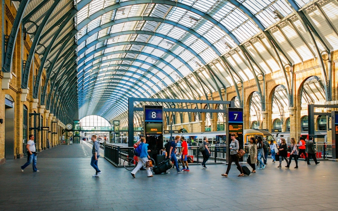 Kings Cross Station interior with travelers and trains, London.