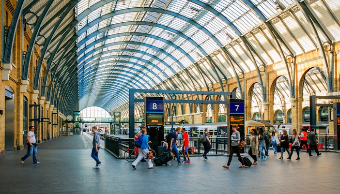 Kings Cross Station interior with travelers and trains, London.