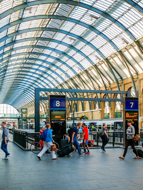Kings Cross Station interior with travelers and trains, London.