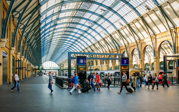 Kings Cross Station interior with travelers and trains, London.