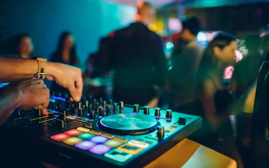 DJ performing at night boat party with colorful lights and dancing crowd.