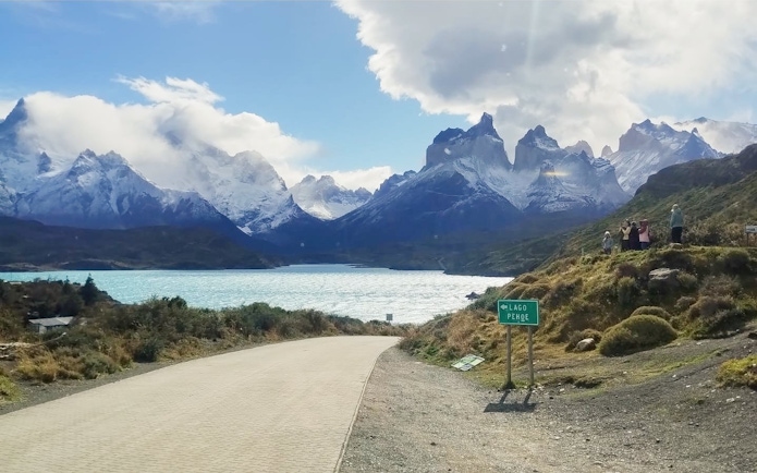 Road leading to Torres del Paine National Park with mountains and Lago Pehoé, Chile.