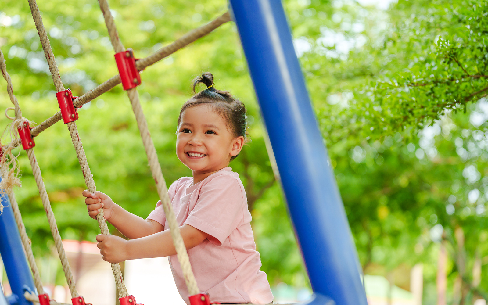 Child climbing rope structure at Jardin Nelson Mandela playground.
