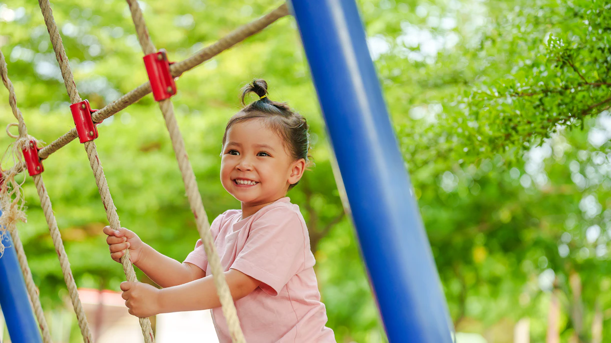 Child climbing rope structure at Jardin Nelson Mandela playground.