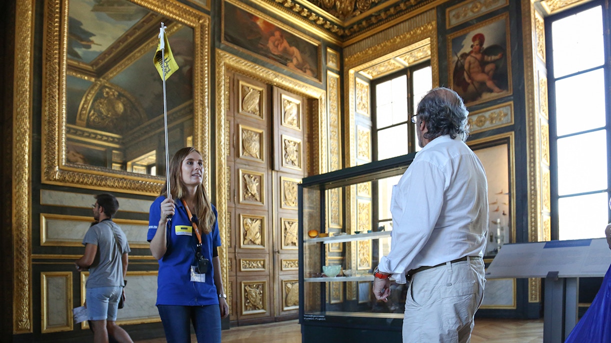 Tour guide leading visitors inside the ornate halls of the Louvre Museum.