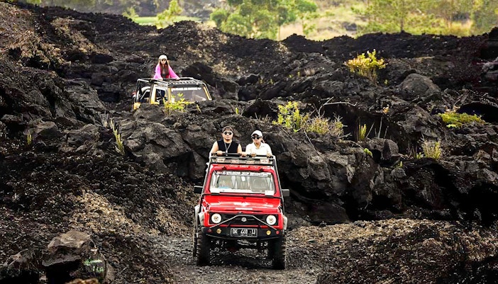 People driving jeeps on black lava trails at Mount Batur, Bali.