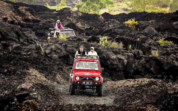 People driving jeeps on black lava trails at Mount Batur, Bali.