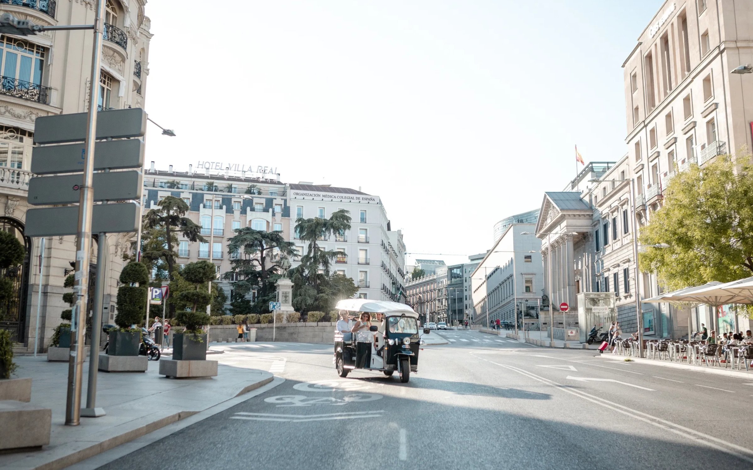 Tourists on an electric tuk-tuk tour in central Madrid street.