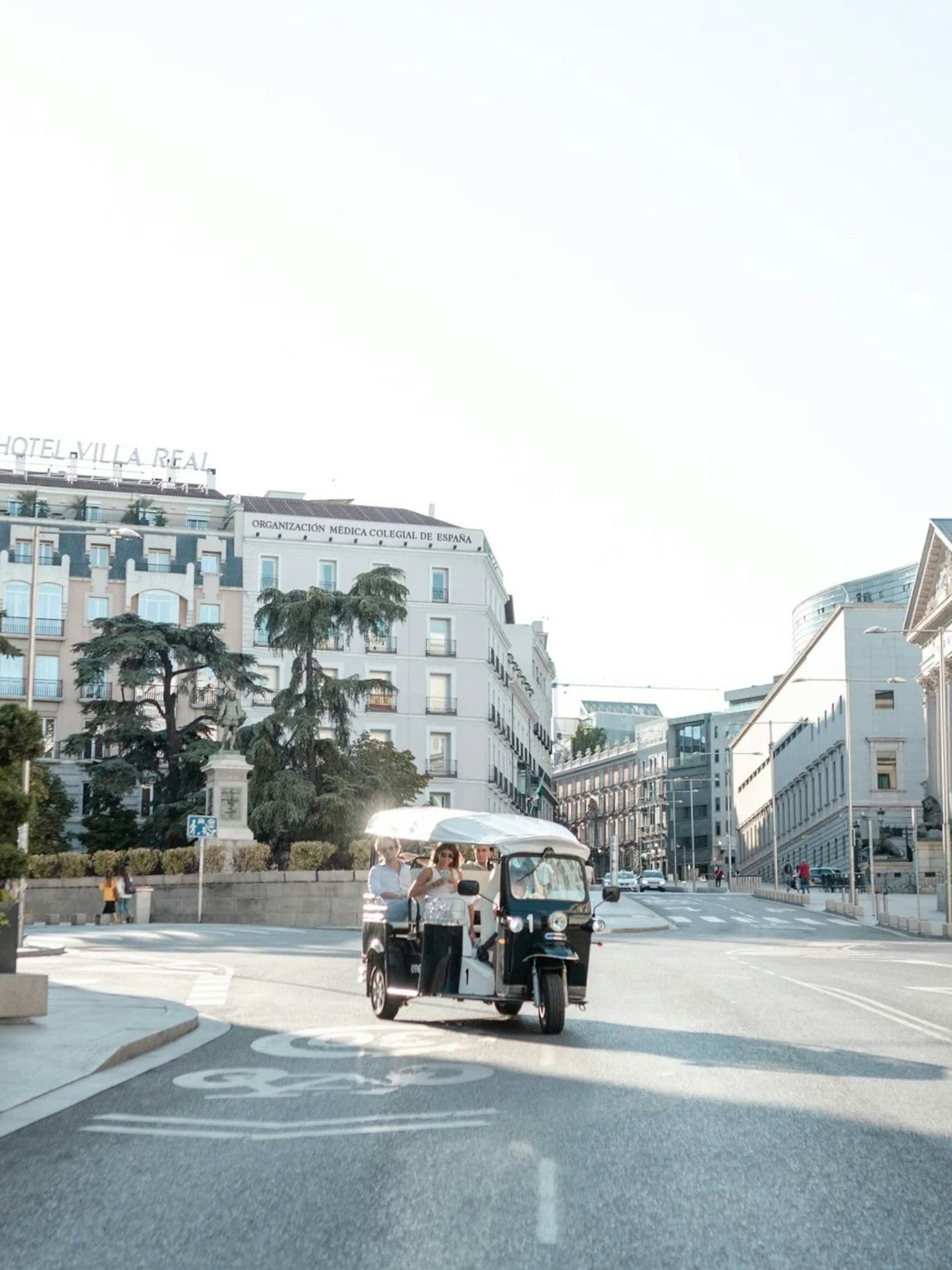 Tourists on an electric tuk-tuk tour in central Madrid street.
