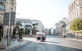 Tourists on an electric tuk-tuk tour in central Madrid street.