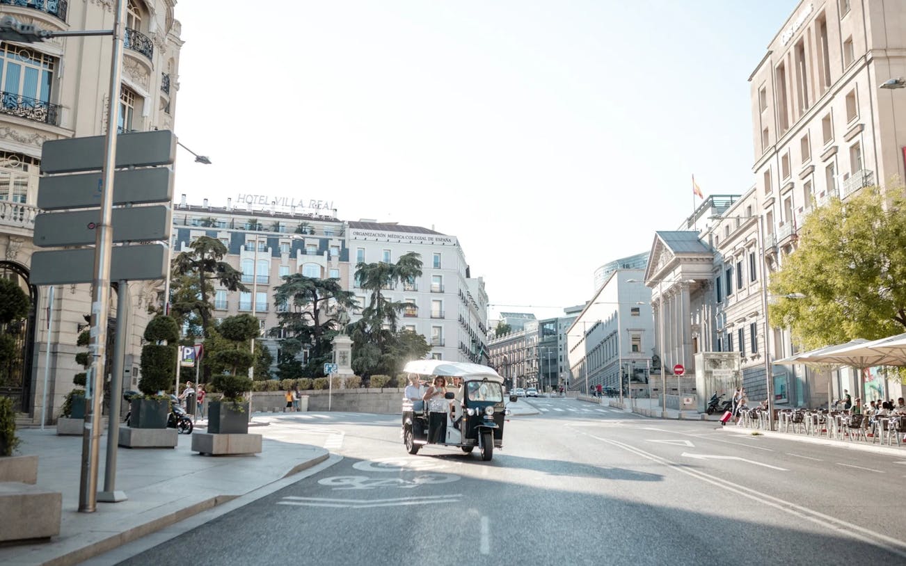 Tourists on an electric tuk-tuk tour in central Madrid street.