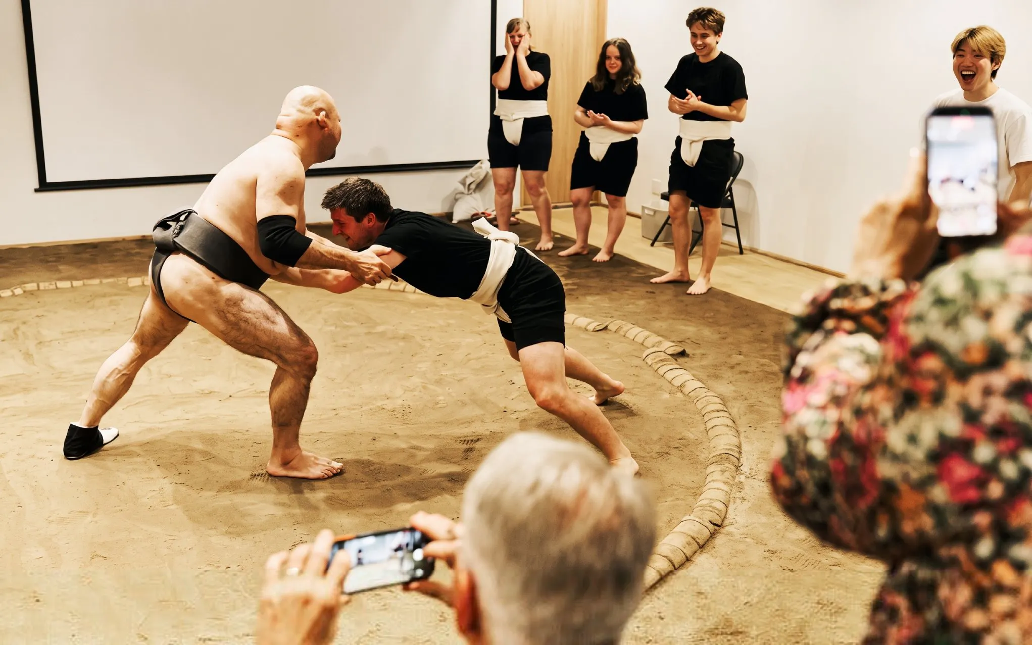 Sumo wrestler and participant engage in a match during Osaka sumo experience.