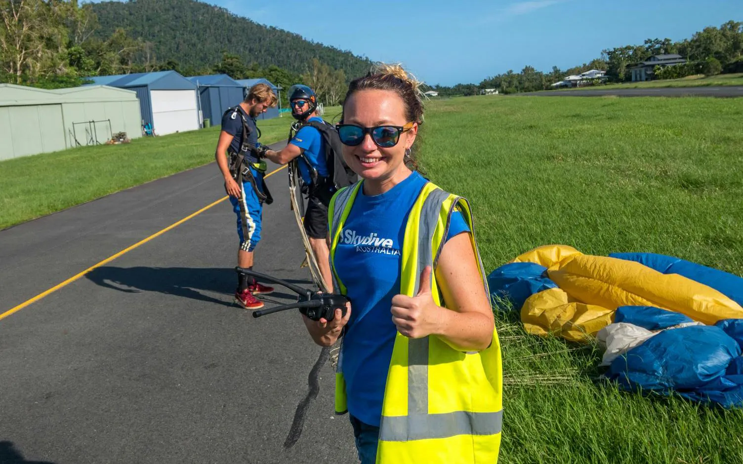 Skydiving team preparing for tandem jump at Airlie Beach runway.