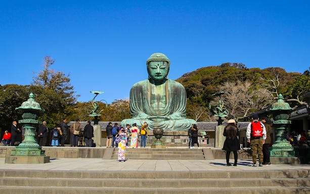 Great Buddha statue at Kotokuin Temple, Kamakura, with visitors exploring the site.