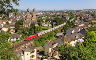 Intercity train passing through a German town with historic church in the background.