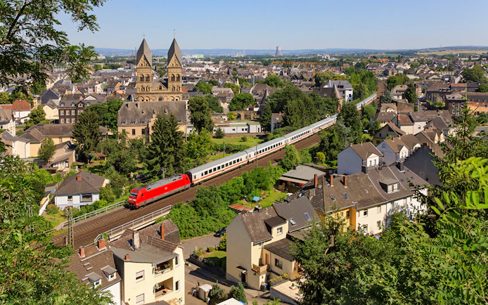 Intercity train passing through a German town with historic church in the background.