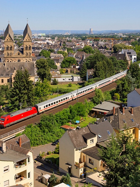 Intercity train passing through a German town with historic church in the background.