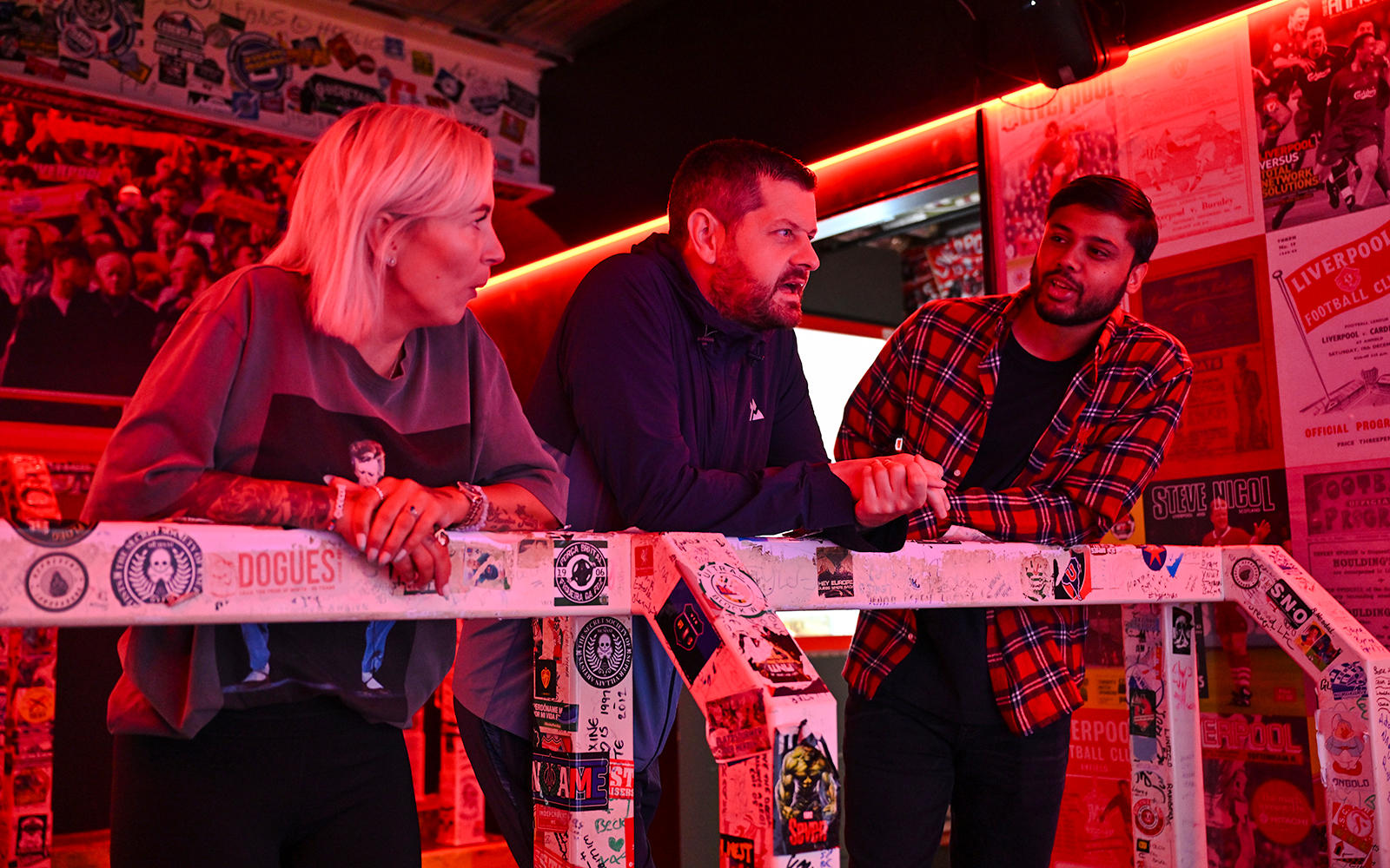 Guests discussing Liverpool FC memorabilia during stadium tour.