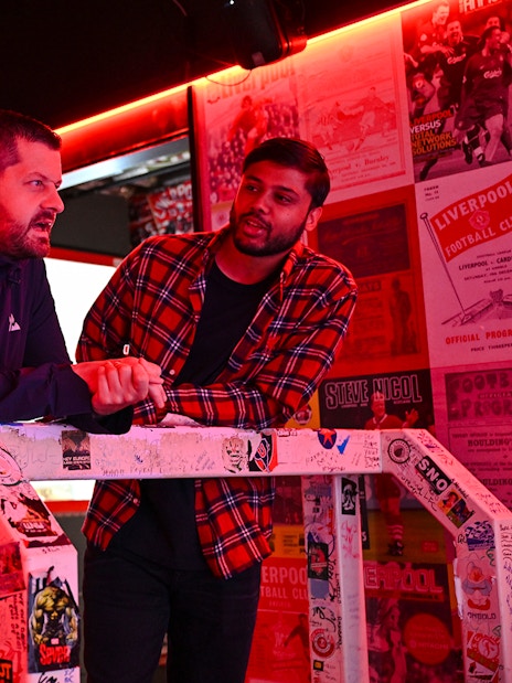 Guests discussing Liverpool FC memorabilia during stadium tour.