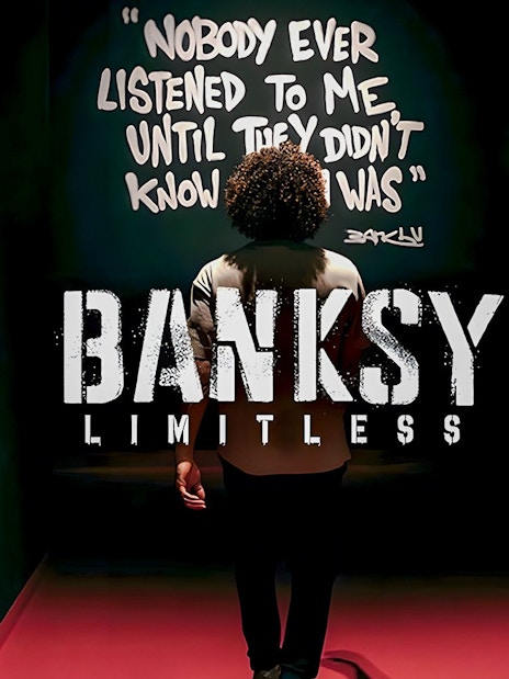 Visitor at Banksy Limitless exhibition viewing artwork with quote on wall.