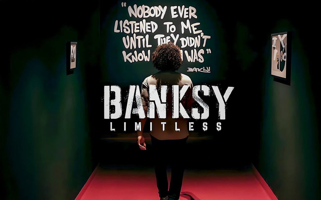 Visitor at Banksy Limitless exhibition viewing artwork with quote on wall.