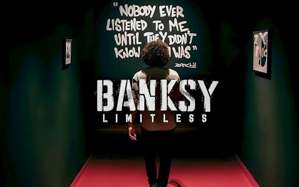 Visitor at Banksy Limitless exhibition viewing artwork with quote on wall.