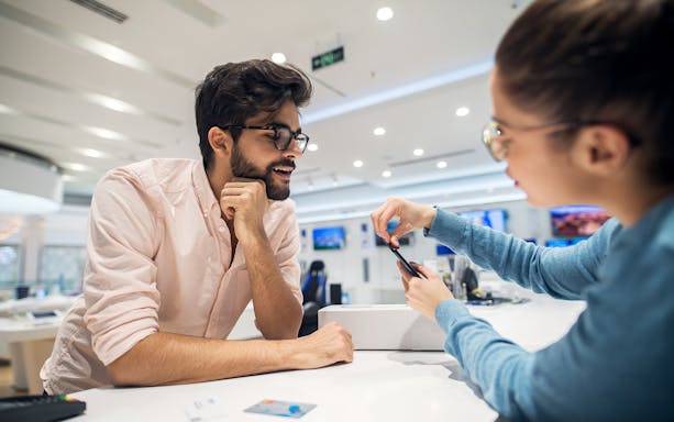 Customer receiving Malaysia 4G eSIM card setup assistance at a store counter.
