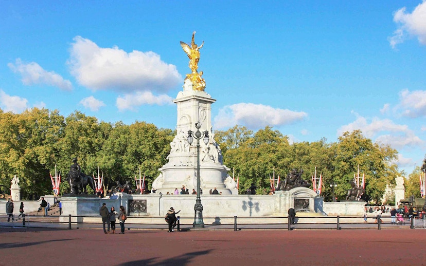 Victoria Memorial near Buckingham Palace, London, with tourists and trees in the background.
