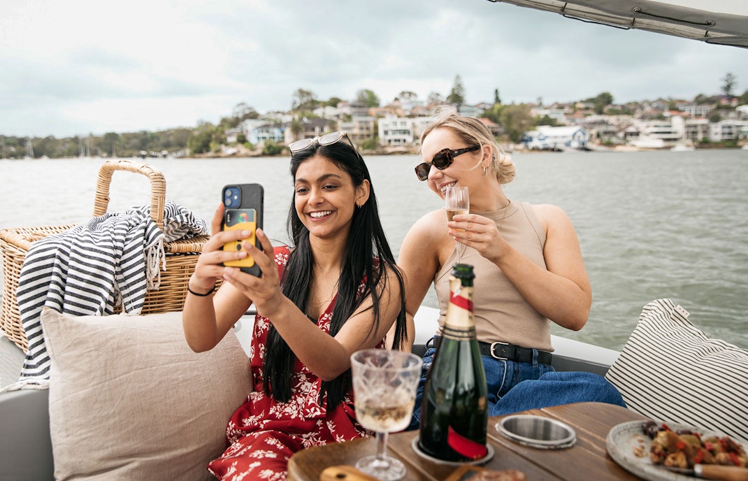 Friends enjoying a picnic on a self-drive electric boat in Sydney.