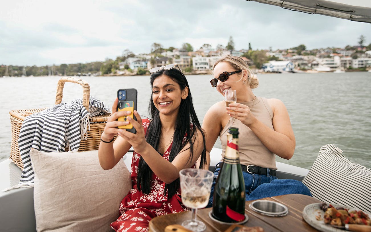 Friends enjoying a picnic on a self-drive electric boat in Sydney.