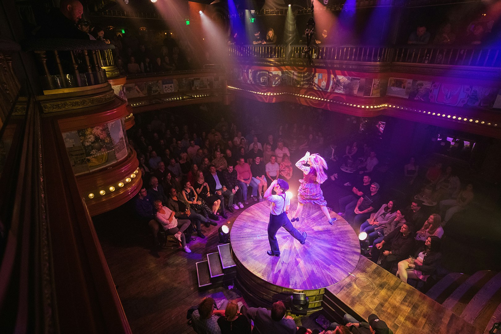 Performers dancing on stage at the Atomic Saloon Show in a vibrant theater setting.
