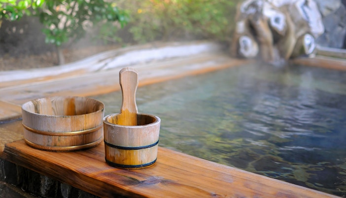 Wooden buckets by a steaming onsen in Kyoto.