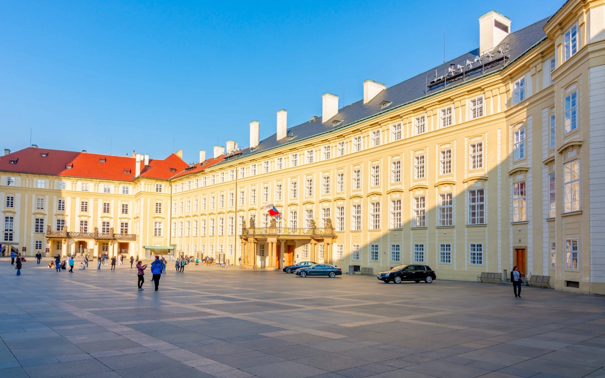 Old Royal Palace at Prague Castle with visitors in the courtyard.
