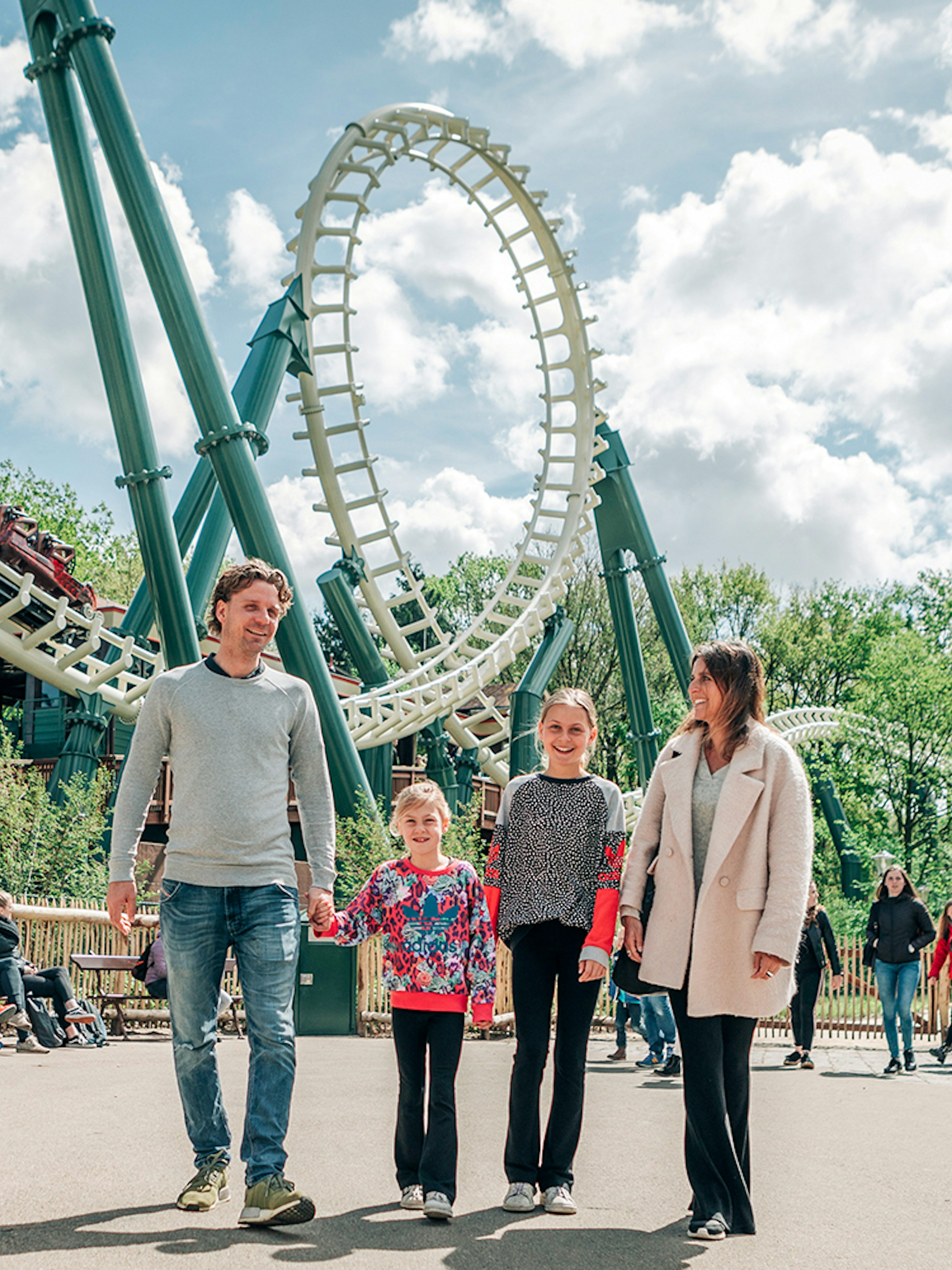 Family walking near roller coaster at Efteling theme park, Netherlands.