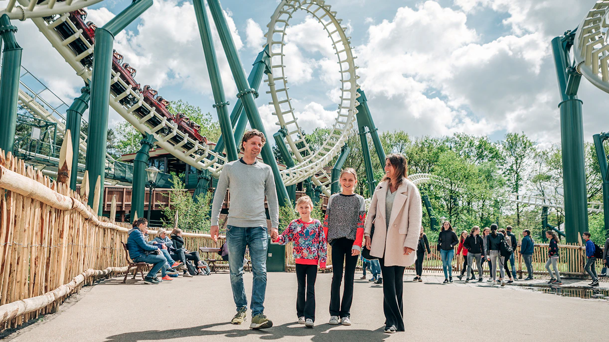Family walking near roller coaster at Efteling theme park, Netherlands.
