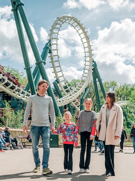 Family walking near roller coaster at Efteling theme park, Netherlands.