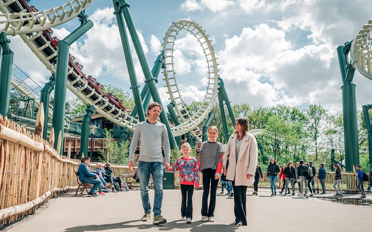 Family walking near roller coaster at Efteling theme park, Netherlands.