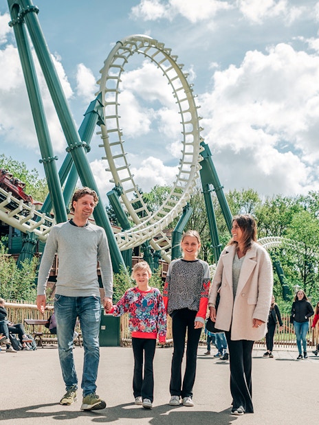 Family walking near roller coaster at Efteling theme park, Netherlands.